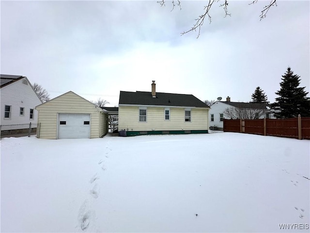 snow covered rear of property with an outbuilding and a garage