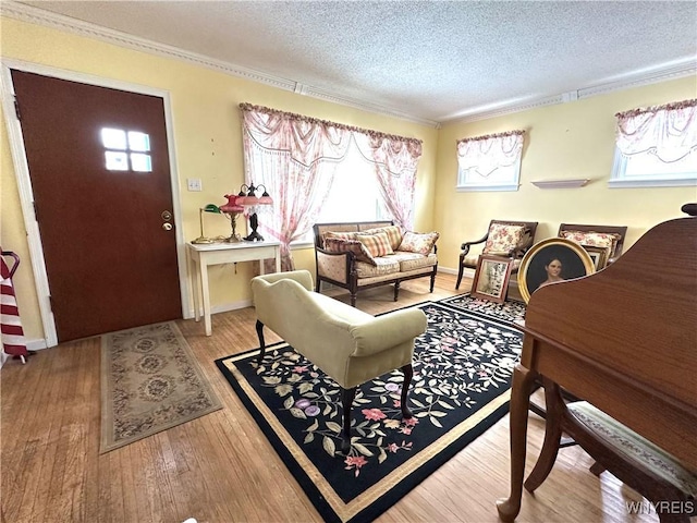 living room featuring ornamental molding, a textured ceiling, and light wood-type flooring