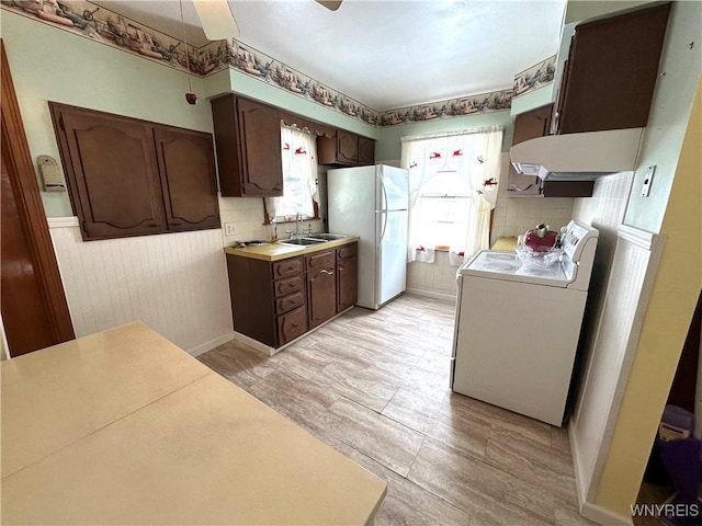 kitchen featuring dark brown cabinetry, washer / clothes dryer, sink, and white fridge