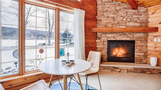 unfurnished room featuring a mountain view, a stone fireplace, and wooden walls