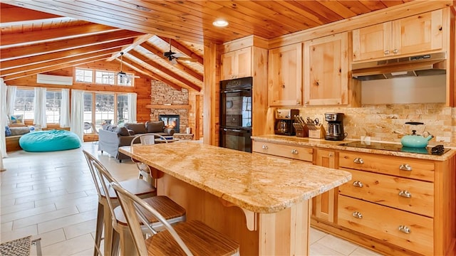 kitchen featuring a kitchen island, a stone fireplace, a wall mounted air conditioner, a kitchen bar, and black appliances