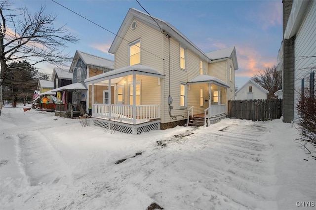 snow covered back of property featuring covered porch