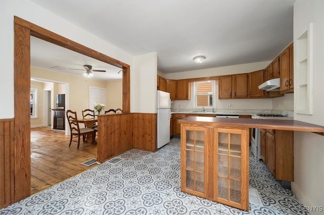 kitchen with stainless steel gas range, sink, white refrigerator, kitchen peninsula, and ceiling fan