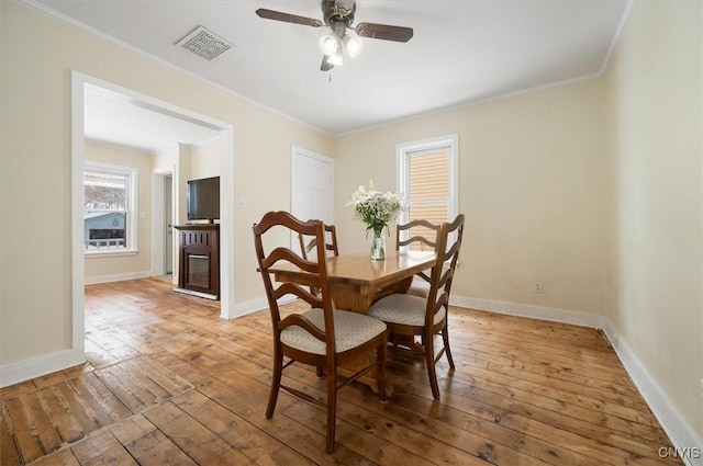 dining area featuring crown molding, ceiling fan, light hardwood / wood-style floors, and a fireplace