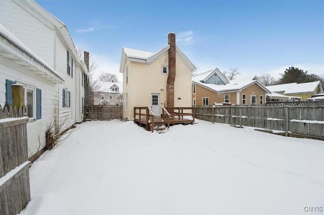 snow covered house with a wooden deck