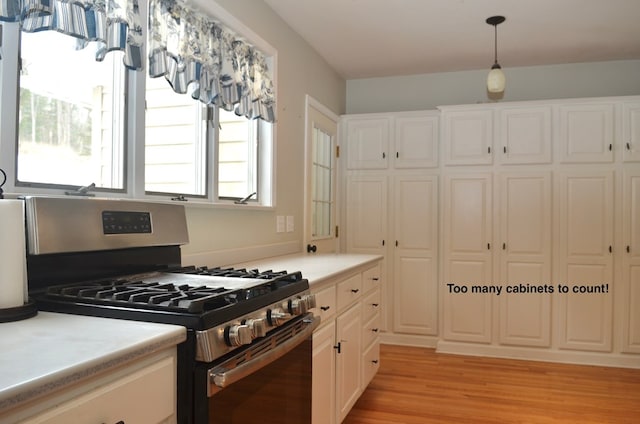 kitchen with stainless steel gas range oven, light countertops, a wealth of natural light, and light wood-style flooring