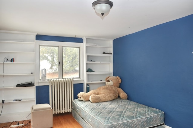 bedroom featuring wood finished floors and radiator