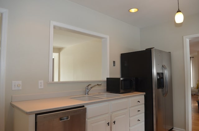 kitchen featuring dishwasher, decorative light fixtures, light countertops, white cabinetry, and a sink