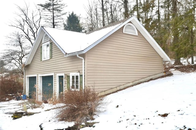 snow covered property with an attached garage