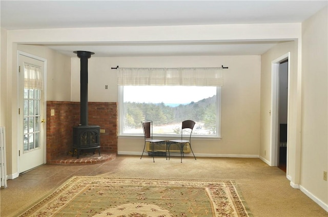 office area with carpet floors, a wood stove, and baseboards