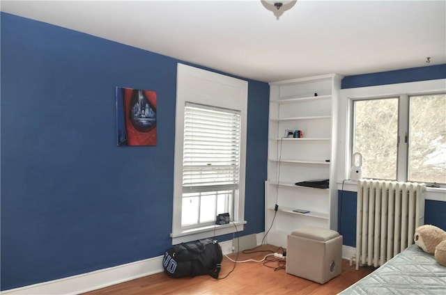 bedroom with radiator, baseboards, and wood finished floors