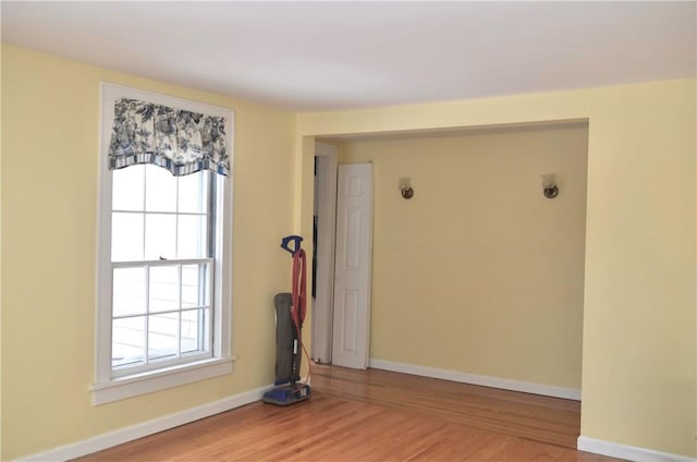 empty room with plenty of natural light, baseboards, and wood finished floors