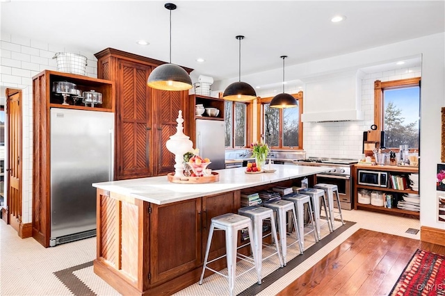 kitchen featuring a center island, appliances with stainless steel finishes, custom range hood, and decorative light fixtures