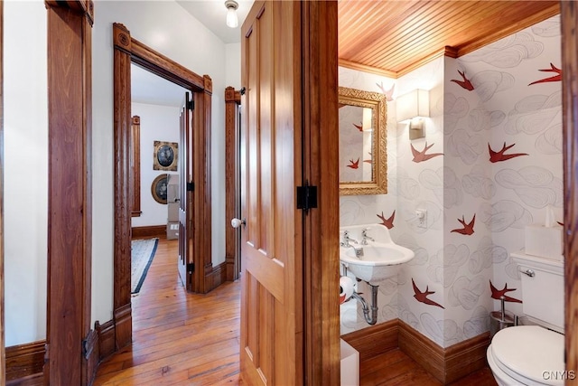 corridor featuring ornamental molding, wooden ceiling, and light wood-type flooring