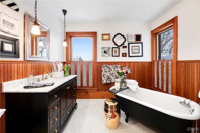 bathroom with vanity, a bath, and wood walls