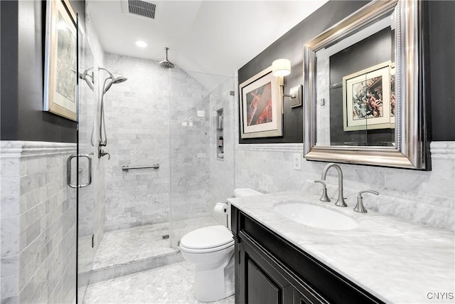 bathroom featuring toilet, tile walls, vanity, and a shower with shower door