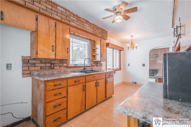 kitchen with tasteful backsplash, ceiling fan with notable chandelier, sink, and pendant lighting