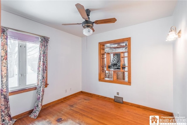 unfurnished room featuring ceiling fan, wood-type flooring, and a wealth of natural light