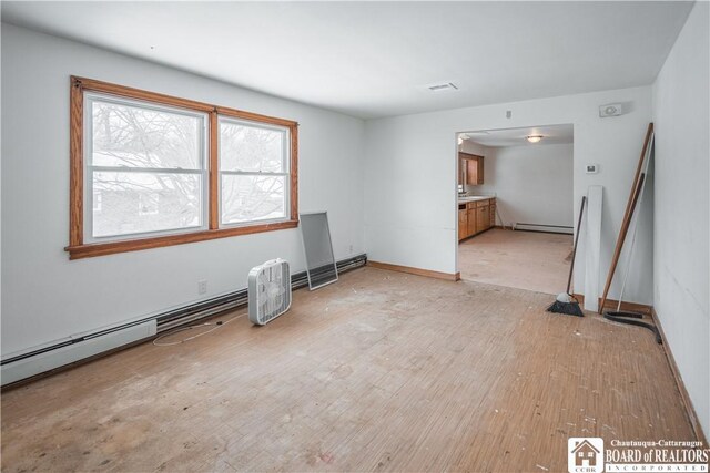 unfurnished room featuring a baseboard heating unit and light wood-type flooring