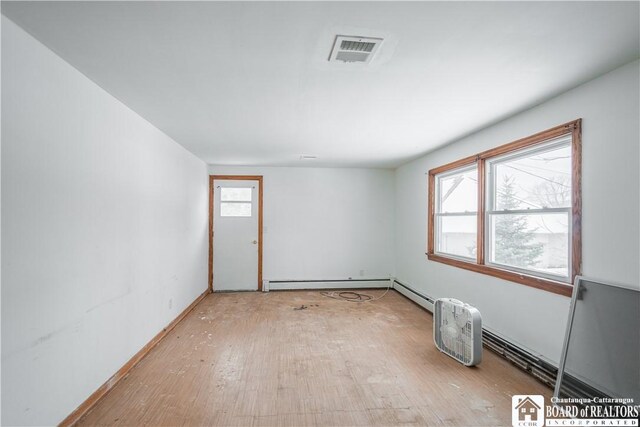 empty room featuring a baseboard radiator and light hardwood / wood-style flooring