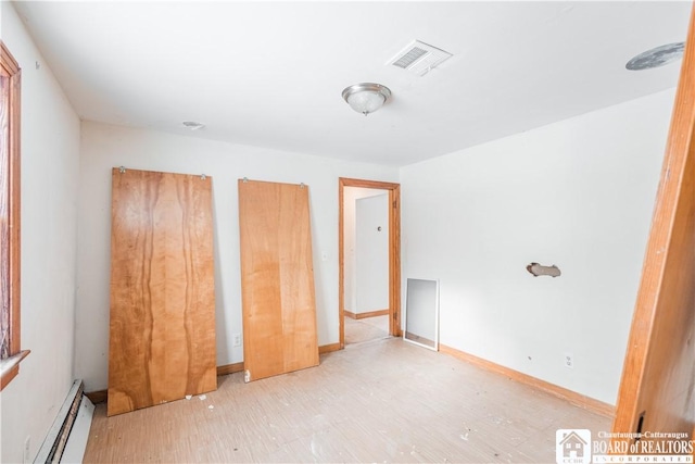 unfurnished bedroom featuring wood-type flooring and baseboard heating