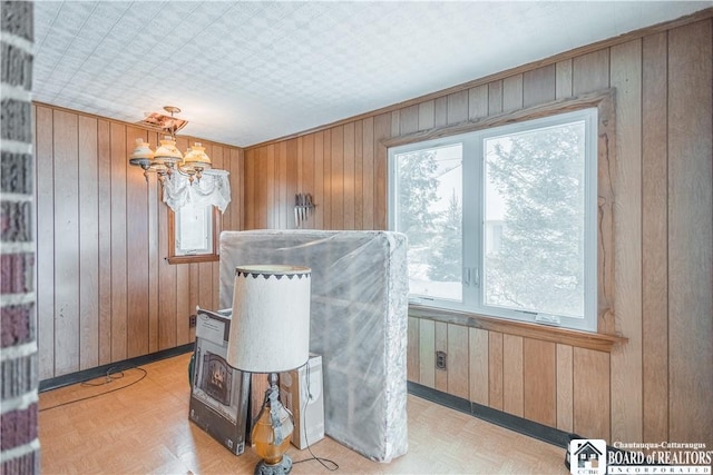 dining room with wooden walls, a chandelier, and light parquet floors