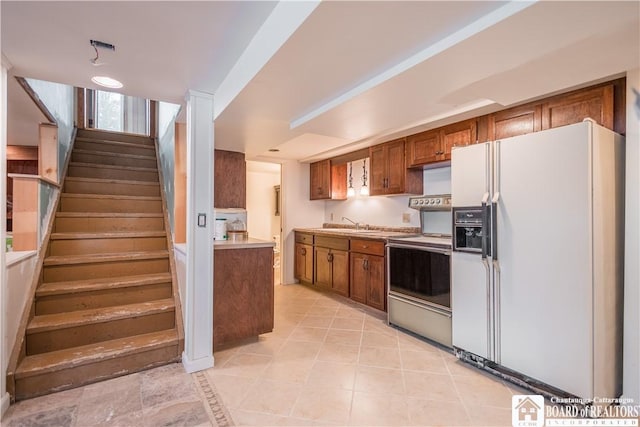 kitchen featuring white fridge with ice dispenser and stainless steel range with electric cooktop