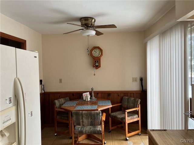 dining room featuring ceiling fan and wood walls