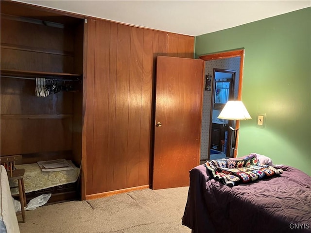 bedroom with light carpet, a closet, and wood walls