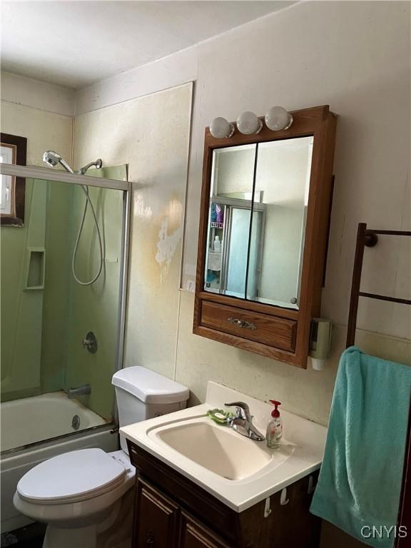 full bathroom featuring vanity, toilet, and combined bath / shower with glass door