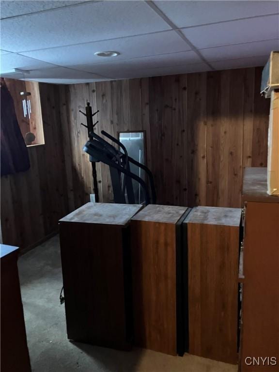 interior space featuring a paneled ceiling and wood walls