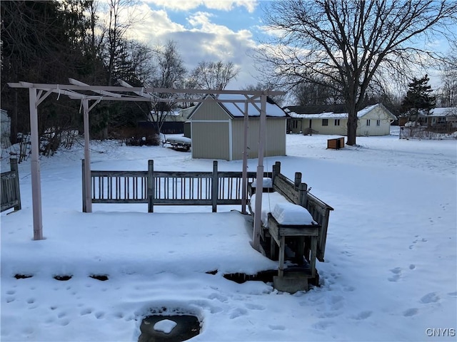 snowy yard with a shed and a deck