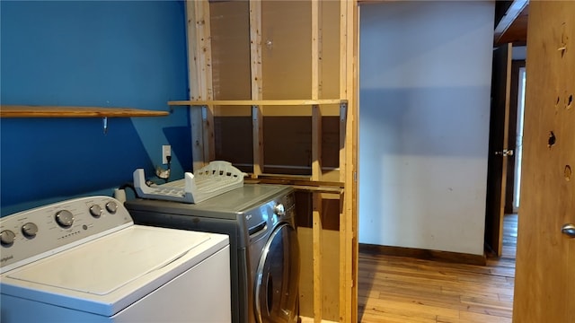 clothes washing area with separate washer and dryer and light wood-type flooring