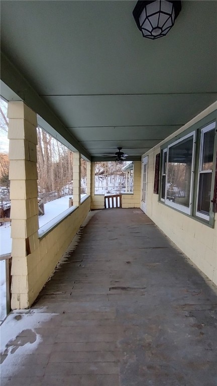 snow covered patio featuring a porch and ceiling fan