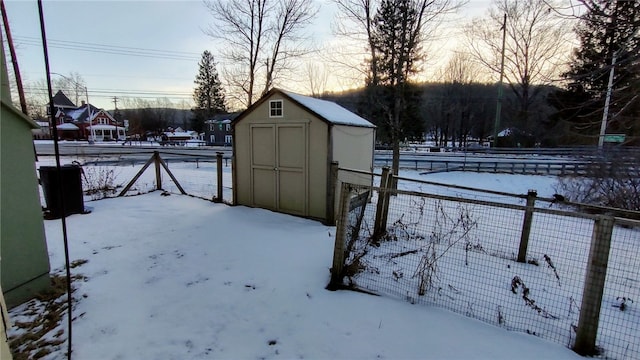 snowy yard featuring a storage unit