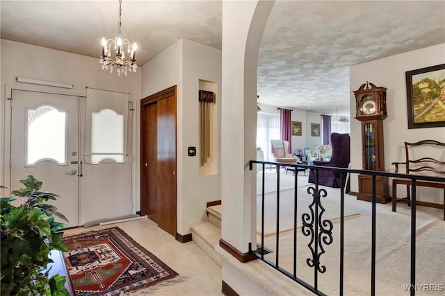 carpeted entrance foyer with a chandelier