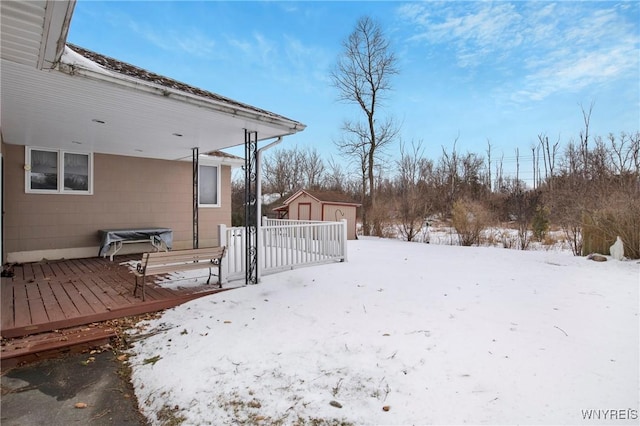 yard layered in snow with a deck and a storage unit