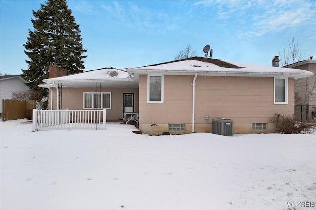 snow covered rear of property featuring a porch and central AC