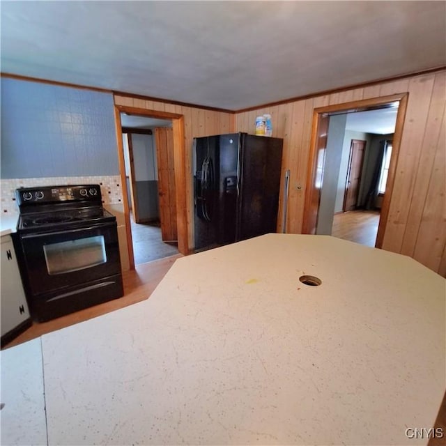 kitchen with backsplash, crown molding, wooden walls, and black appliances