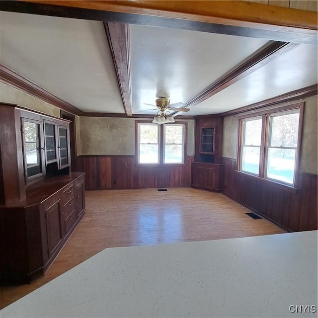 living room featuring ceiling fan, wooden walls, beam ceiling, and light hardwood / wood-style floors