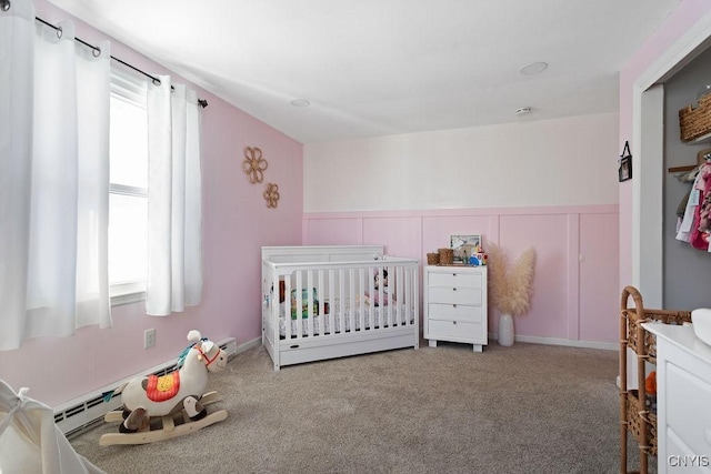 carpeted bedroom featuring a crib and a baseboard radiator