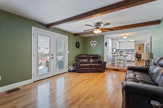 living room with french doors, beamed ceiling, ceiling fan, and light wood-type flooring