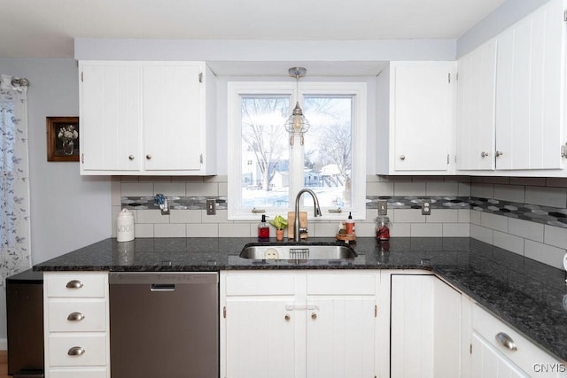 kitchen featuring dishwasher, sink, white cabinets, dark stone counters, and hanging light fixtures