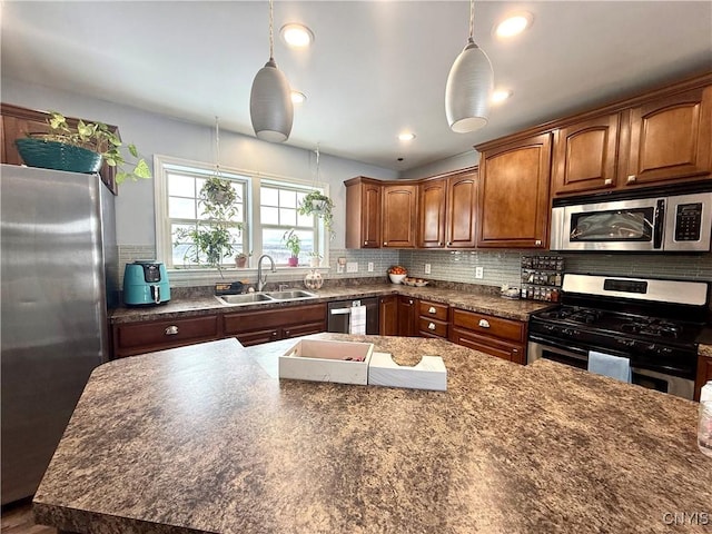 kitchen featuring appliances with stainless steel finishes, decorative light fixtures, sink, and decorative backsplash