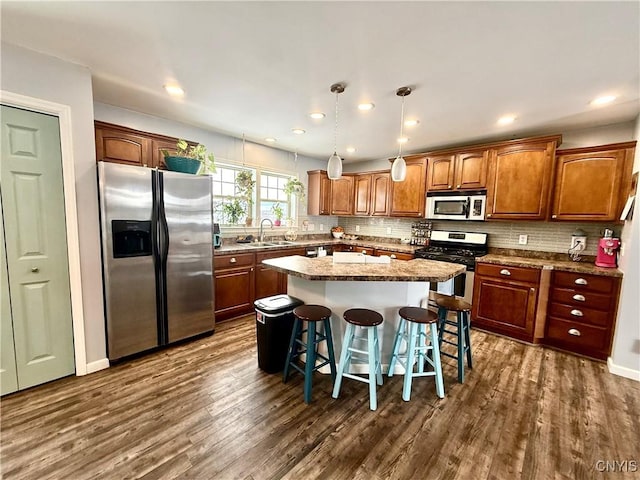 kitchen with pendant lighting, sink, a breakfast bar, stainless steel appliances, and a center island