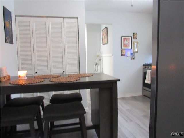 kitchen featuring wood-type flooring, stainless steel range with gas stovetop, and a kitchen breakfast bar