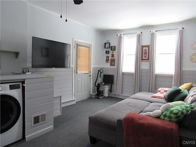 living room featuring dark colored carpet, washer / dryer, and crown molding