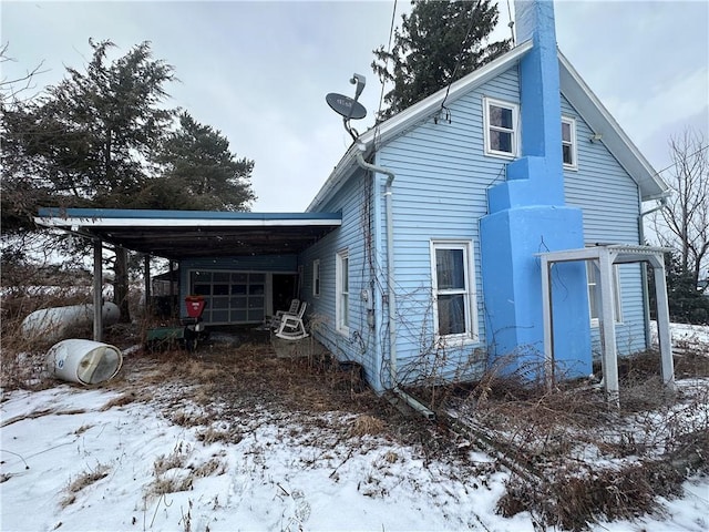 view of snowy exterior featuring a carport