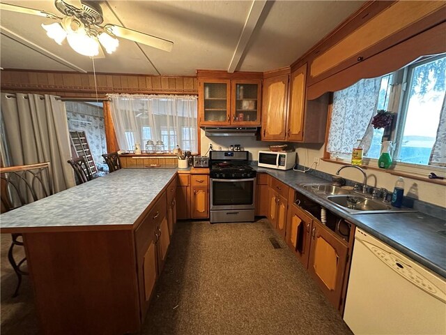 kitchen featuring white appliances, a breakfast bar, sink, wood walls, and ceiling fan