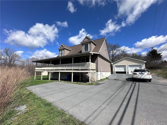 view of front facade with a porch, a garage, an outdoor structure, and a front lawn